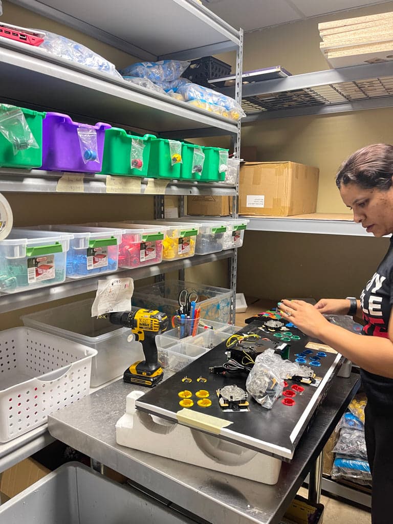 A team member assembling arcade joysticks and buttons